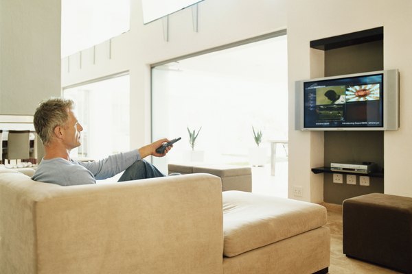 Digital Vision./Digital Vision/Getty Images Mature Man Sits Watching TV in a Modern Home Interior