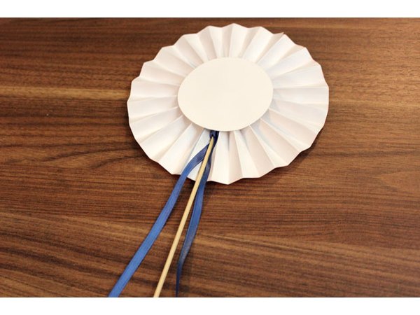 Hot glue a dowel and ribbon to the rosette