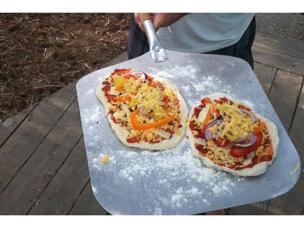 A proud pizza chef displays the finished meal.