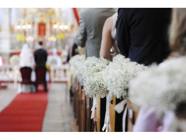 A bride and groom stand at the front of the aisle.