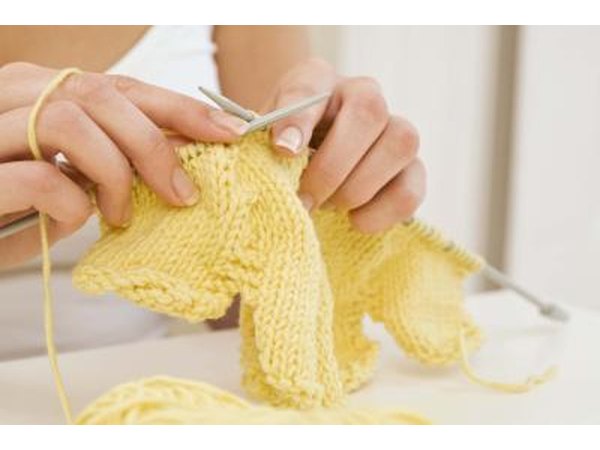 hands knitting with yellow yarn
