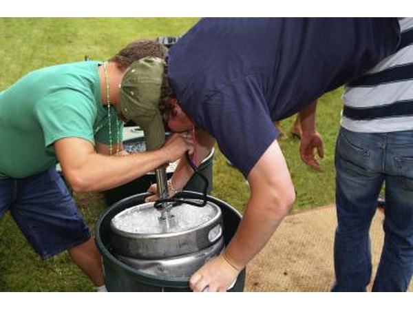 Man drinking keg beer while doing a hand stand