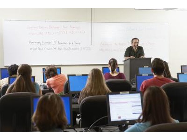 Teacher instructing students with computers in classroom