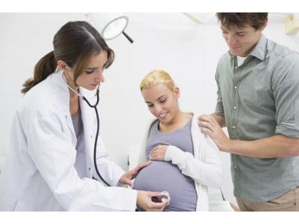 obstetrician listting to pregnant woman's stomach
