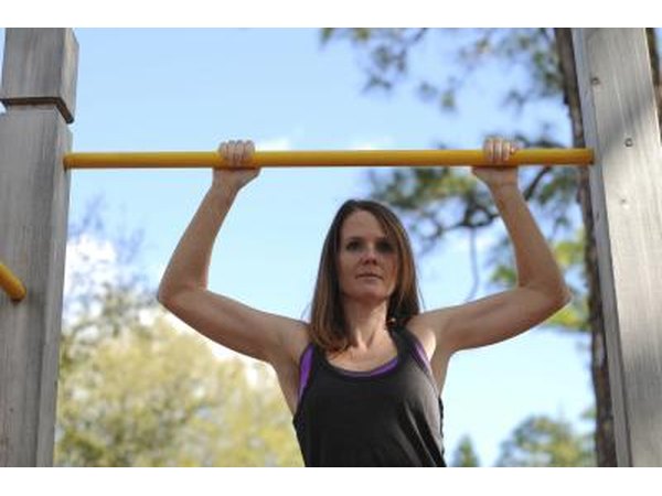 A woman is doing pullups outdoors.