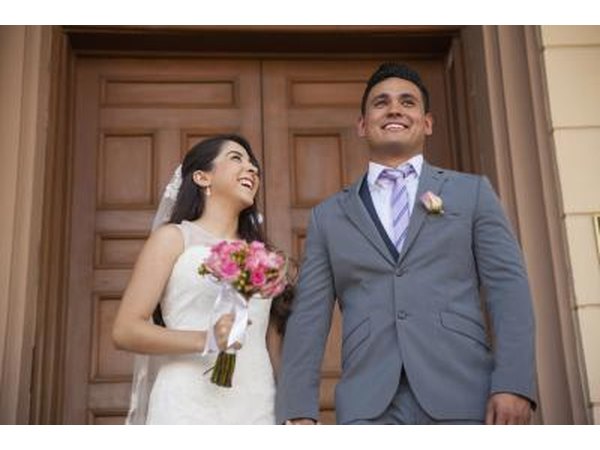 A happily married couple standing on the front steps of a courthouse.