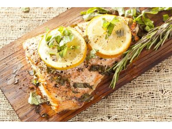 Grilled salmon with lemons and herbs on wood board