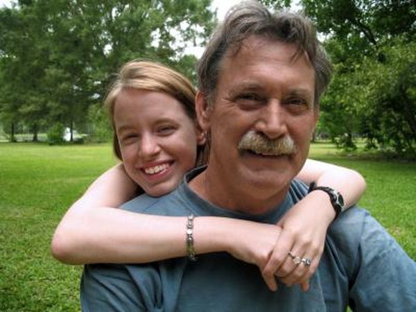 A teenager gives her dad a hug outside.