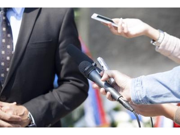 Journalists holding out microphones to politician.