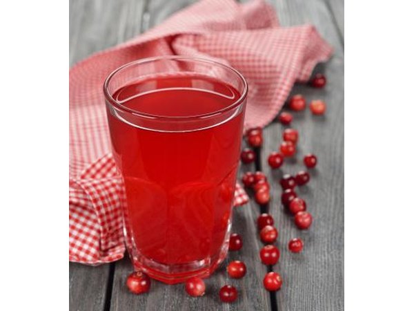 A glass of cranberry juice on a table with cranberries