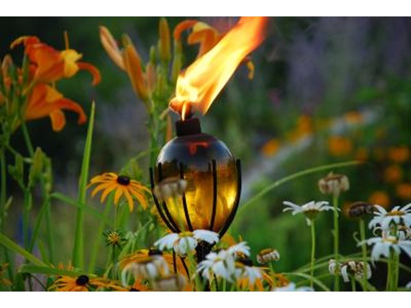 A tiki torch sits amongst tropical flowers.