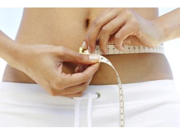Woman measuring waist with measuring tape.