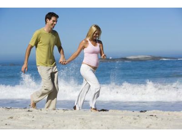 pregnant couple jogging on beach