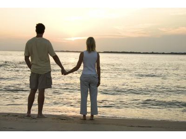 A couple holds hands and watches the sunset.