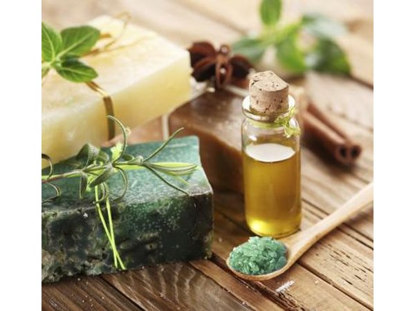 Natural soaps next to a bottle of essential oil and herbs