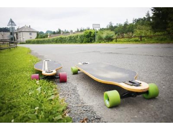 Two downhill skateboards on the side of the road.