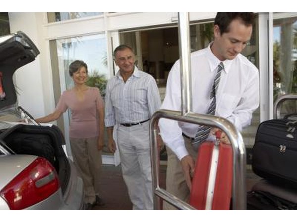 A hotel employee assists guests with their luggage.