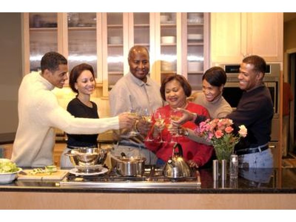 Friends toasting wine glasses in kitchen.