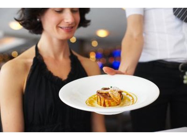 A waiter presents an appetizer to a patron.
