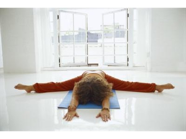 A woman does tortoise pose on a mat.