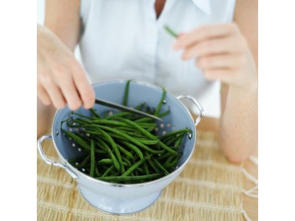 A woman cuts green beans.