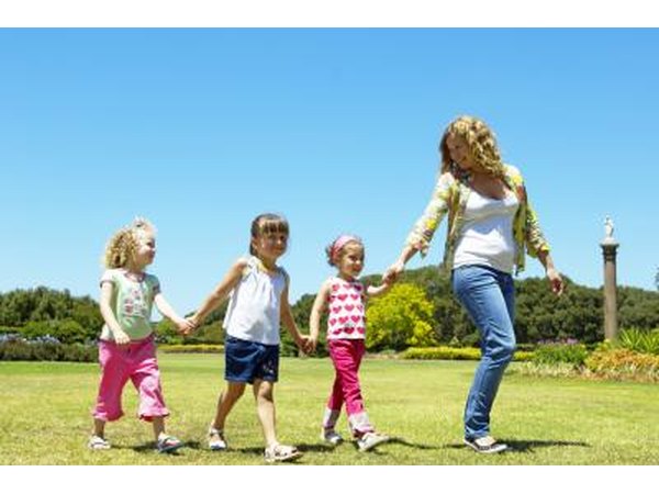 A nanny takes three girls to the park.
