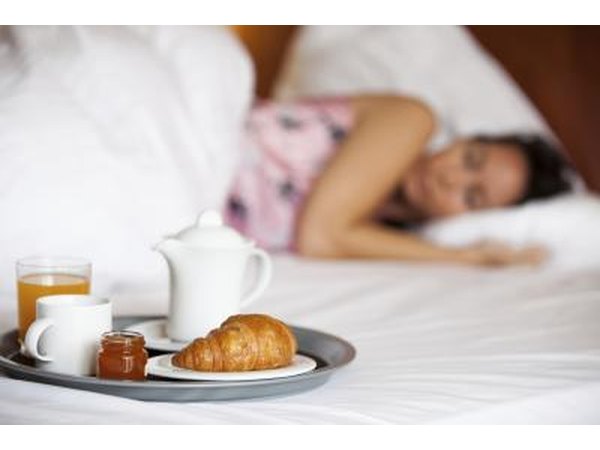 Woman lying in bed next to breakfast