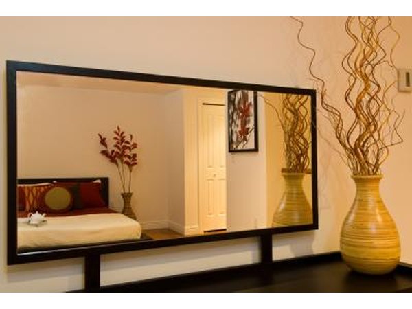 The reflection of a bedroom in a rectangular mirror.