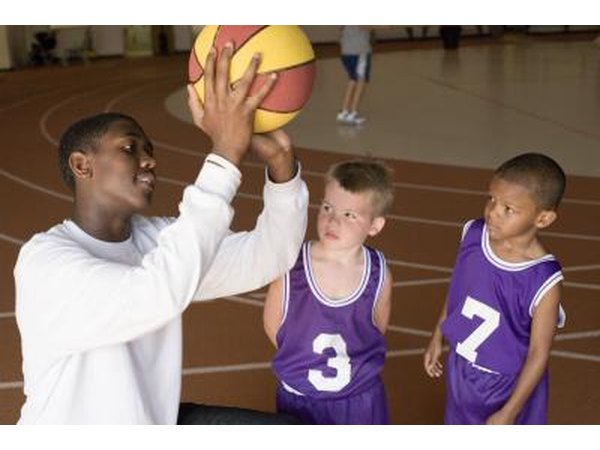 Coach teaching kid to shoot basketball