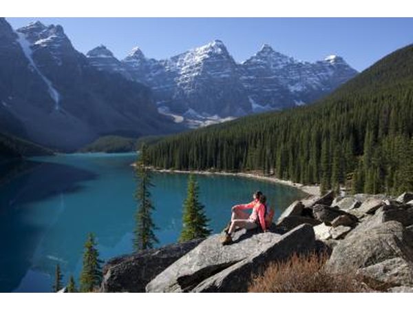 A woman hikes near a mountain lake in the Rockies.