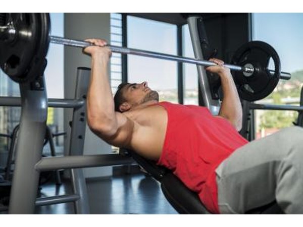 A man performs a bench press work out in a weight room.