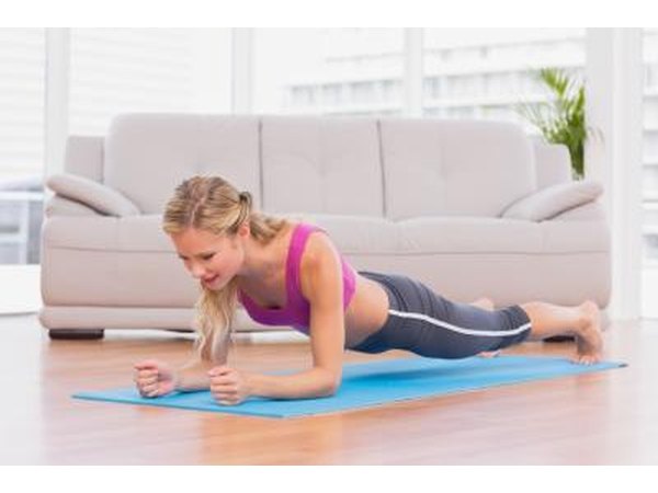 Young woman doing the plank position on yoga mat.
