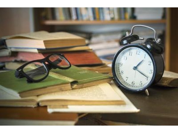Vintage books, eye glasses, and clock on a desk.