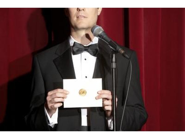 Man in tuxedo announcing award recipient