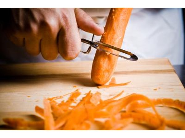 A cook peels a carrot.