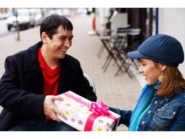 A woman gives a smiling man a present.