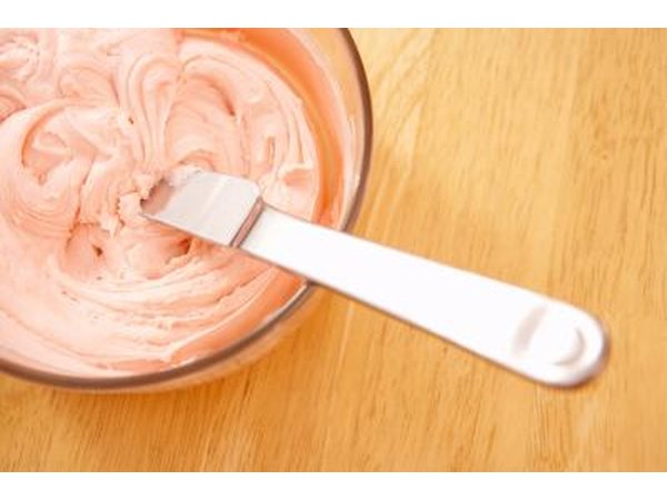 Pipe frosting onto cake to write baby-themed words.