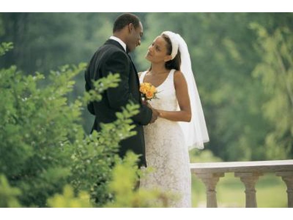 Bride and groom embrace in park