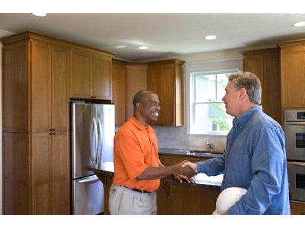 Two men shake hands in a kitchen.