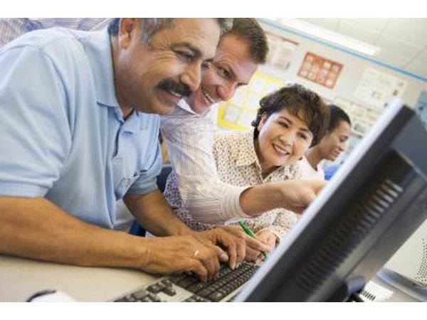 A mature student works at a computer with an instructor.