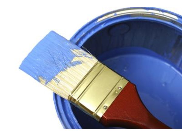 Paint can and paintbrush in blue paint.