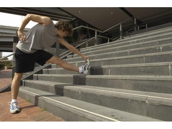 A man is stretching his legs on an outdoor staircase.