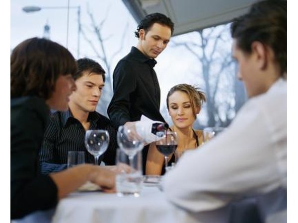 A server pours wine at a table.