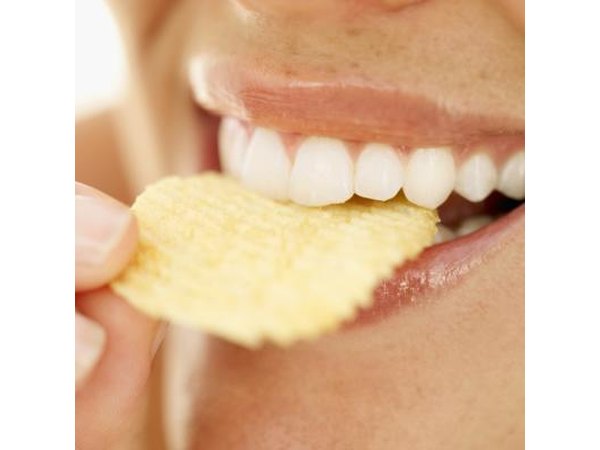 A close-up of a woman eating a potato chip.