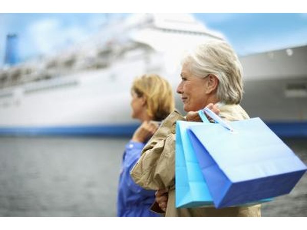 Two woman with shopping bags stand at a port in front of a cruise ship.
