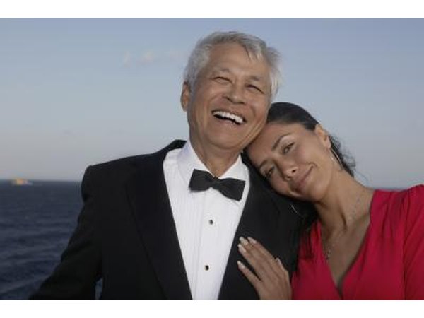 A couple in formal wear on the deck overlooking the water.