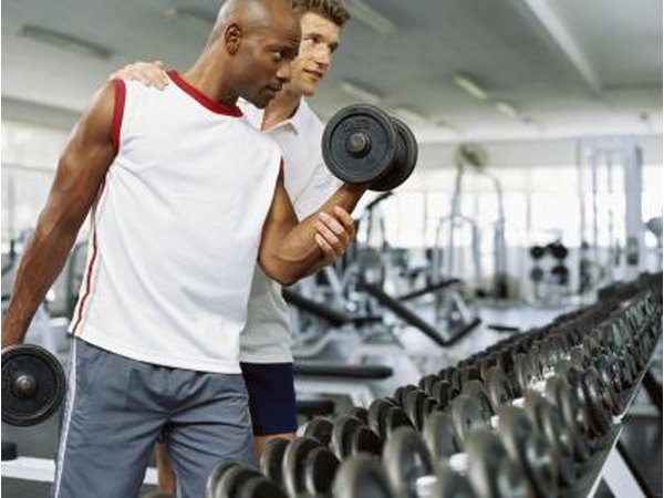 A man works with a personal trainer at a gym.