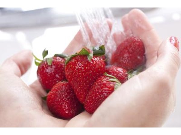 A woman washes fresh strawberries.