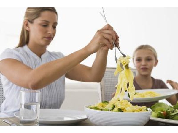 woman serving pasta to child
