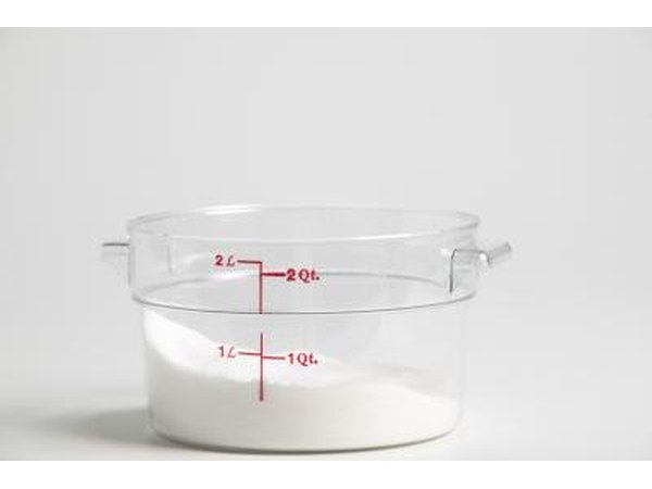 A measuring cup partially filled with cane sugar.